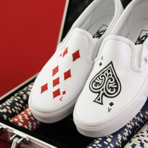 Custom, hand painted poker card vans displayed on a game table with poker chips.